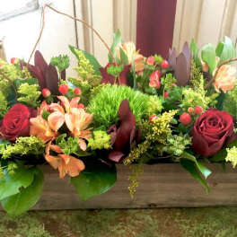 Rectangular floral arrangement with red roses and peach flowers in a wooden box