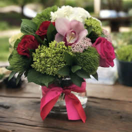 Bouquet of red and pink roses with a pink orchid in a glass vase