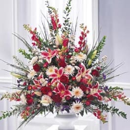 Large red and white floral arrangement in a white pedestal vase