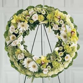 Circular floral wreath with white and pale yellow flowers on a stand