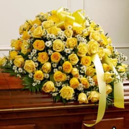 Yellow rose casket spray with white filler flowers and ribbon