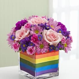 Pink roses and purple daisies in a rainbow-striped vase