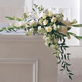 White floral arrangement draped over a casket