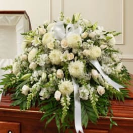 White funeral spray with lilies and roses on a casket