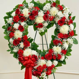 Heart-shaped wreath of red and white flowers with a red ribbon bow