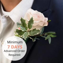 Blush rose boutonniere with variegated foliage pinned to a dark suit jacket, with text noting 7 days advance order.