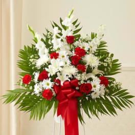 Standing floral spray with red and white flowers and a red ribbon