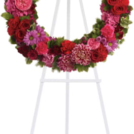 Circular floral wreath on a white easel with pink and red flowers