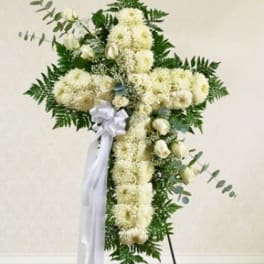 White floral standing cross with ribbon on an easel
