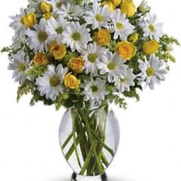 White daisies and yellow roses in a clear glass vase