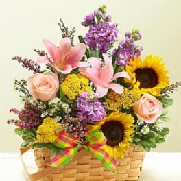 Basket arrangement with sunflowers, pink roses, and purple flowers