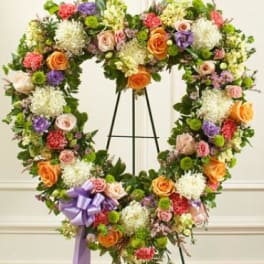 Heart-shaped floral wreath on an easel with mixed roses and chrysanthemums