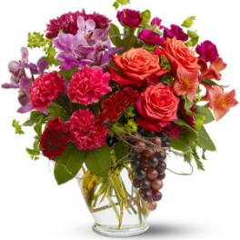 Mixed bouquet of roses, carnations, orchids, and lilies in a glass vase