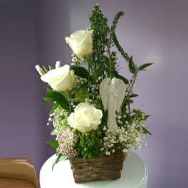 White roses in a basket with a small angel figurine