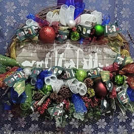 Christmas wreath with ribbon bows and ornaments around a wooden sign