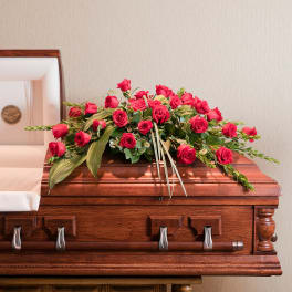 Red rose spray arranged on a wooden casket