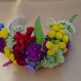 Colorful floral wrist corsage with yellow, purple, red, and blue blooms
