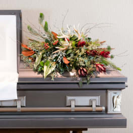 Floral spray on top of a casket with red and green accents