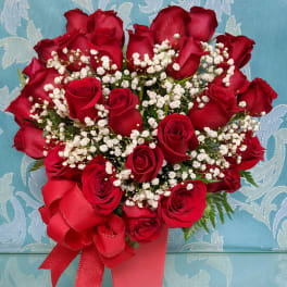 Red roses with white baby's breath in a pink vase and ribbon