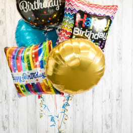 Cluster of birthday balloons with a candle and small gift on a table