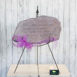 Memorial stone on a metal stand with a purple ribbon and candle