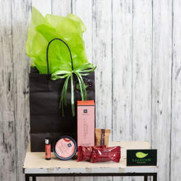 Gift bag with tissue paper, candles, and candy on a small table