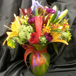 Colorful mixed bouquet in a green vase with a ribbon bow