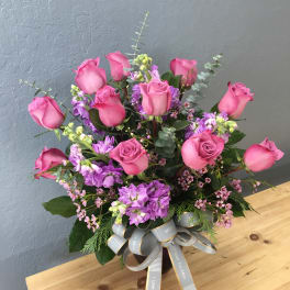 Pink roses and purple flowers in a vase with a ribbon bow