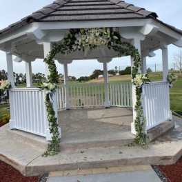 White floral garland decorates a gazebo with greenery and white blooms.