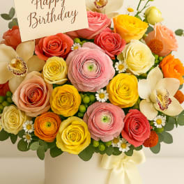 Colorful mixed flower arrangement in a cream box with a Happy Birthday card