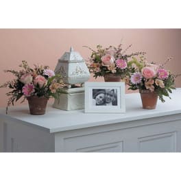 Three pink floral arrangements with a framed photo and decorative lantern
