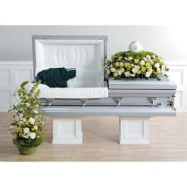 Casket with white and yellow floral sprays in a funeral room