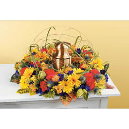 Colorful floral arrangement surrounding a bronze urn on a white table