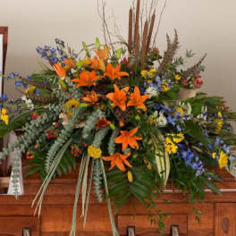 Large floral spray with orange lilies and mixed flowers on a casket