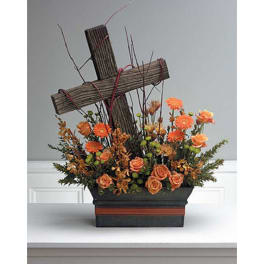 Orange flowers arranged around a wooden cross in a rectangular container