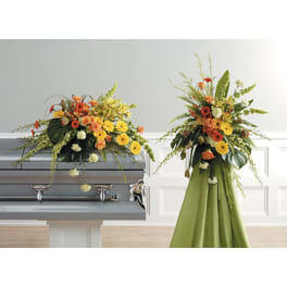Two floral funeral arrangements on and beside a casket