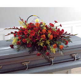 Red and orange floral casket spray on a gray casket