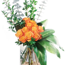 Orange roses in a clear vase with tall greenery