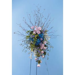 Tall floral arrangement with pink and blue flowers and bare branches