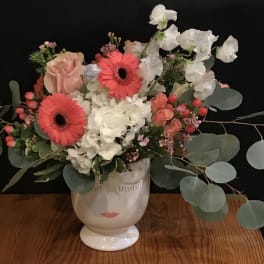 Bouquet of pink gerberas, white hydrangeas, and roses in a face vase