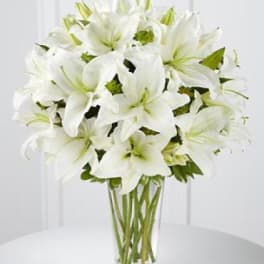 White lilies arranged in a clear glass vase