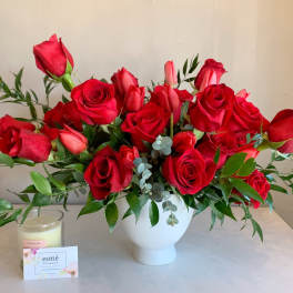 Red roses arranged in a white vase with greenery