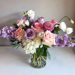 Mixed bouquet of pink, lavender, and white flowers in a glass vase
