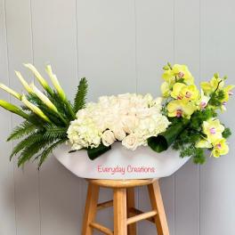 White floral arrangement with calla lilies, roses, hydrangea, and yellow orchids