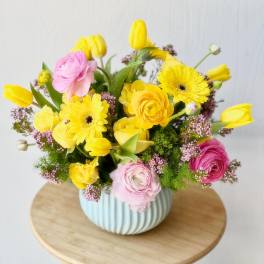 Yellow and pink mixed flowers arranged in a ribbed blue vase