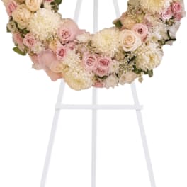 Pastel floral wreath of pink and cream flowers on a white stand