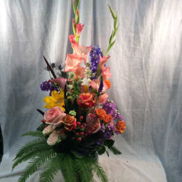 Tall mixed bouquet with pink, purple, orange, and yellow flowers in a vase