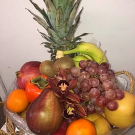 Fruit basket with grapes, bananas, citrus, pears, mango, and orchids