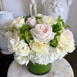 White and pale pink roses arranged in a green vase