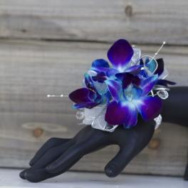 Purple-blue orchid corsage on a black mannequin hand